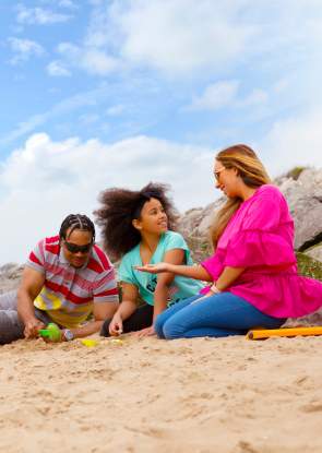 A family on the beach in Wirral building sandcastles on a clear day