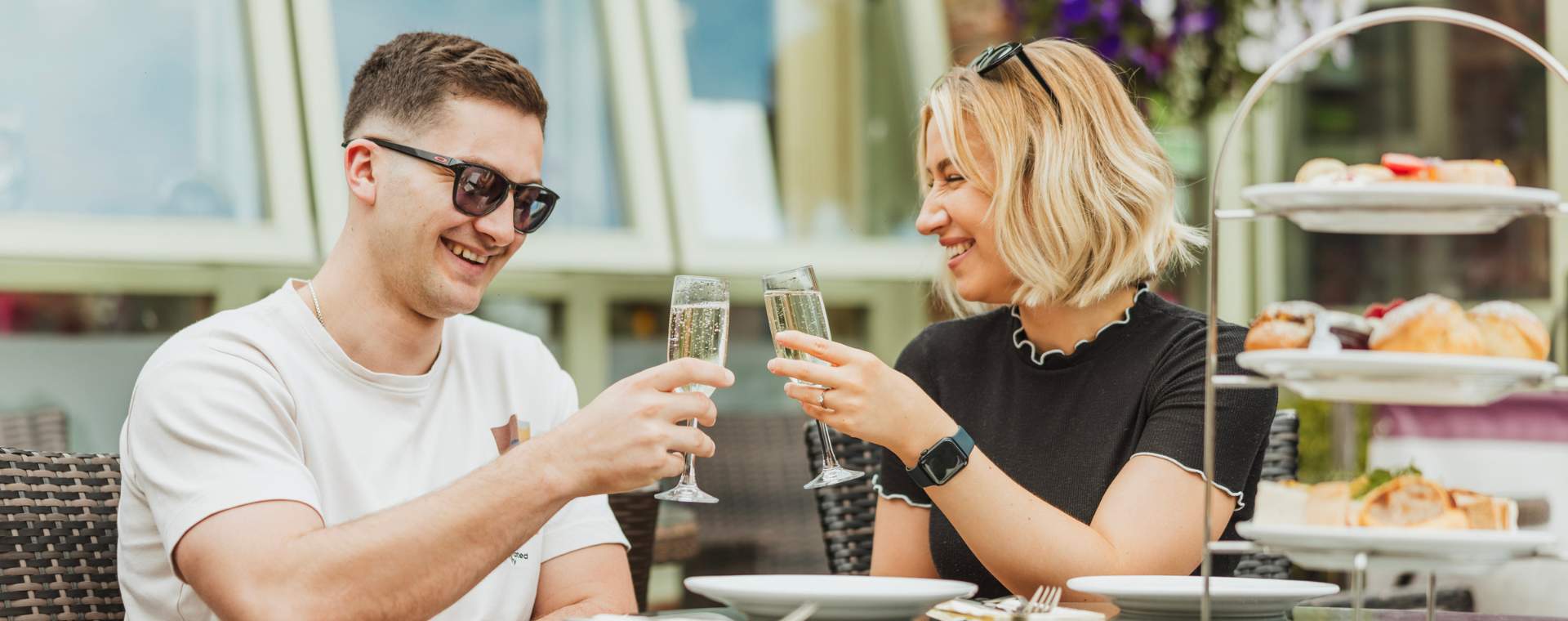 A couple clinking Champagne classes while they enjoy afternoon tea at Drewton's in East Yorkshire