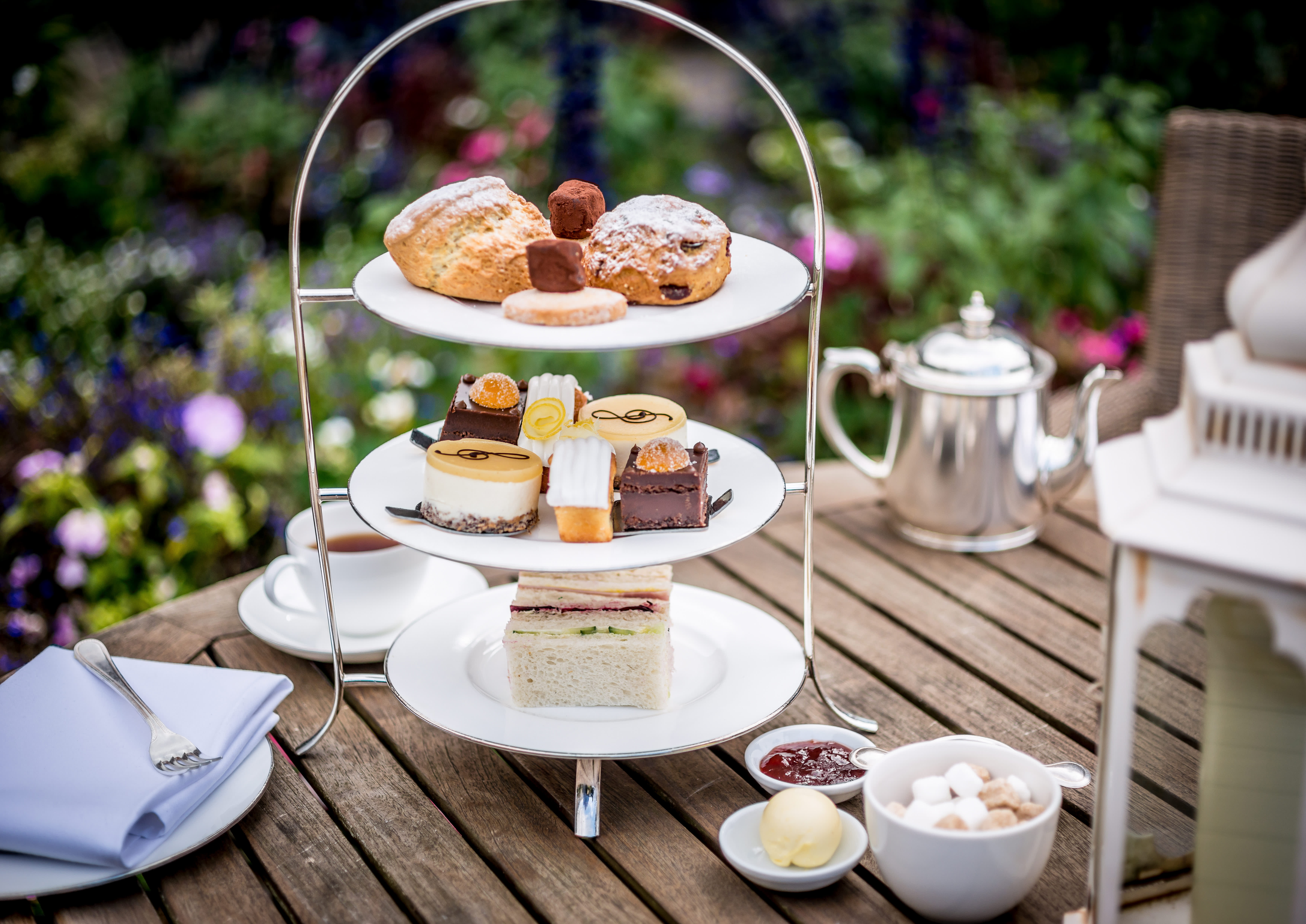 Three tiered afternoon tea selection of cakes, sandwiches and a tea pot at Amberley Castle