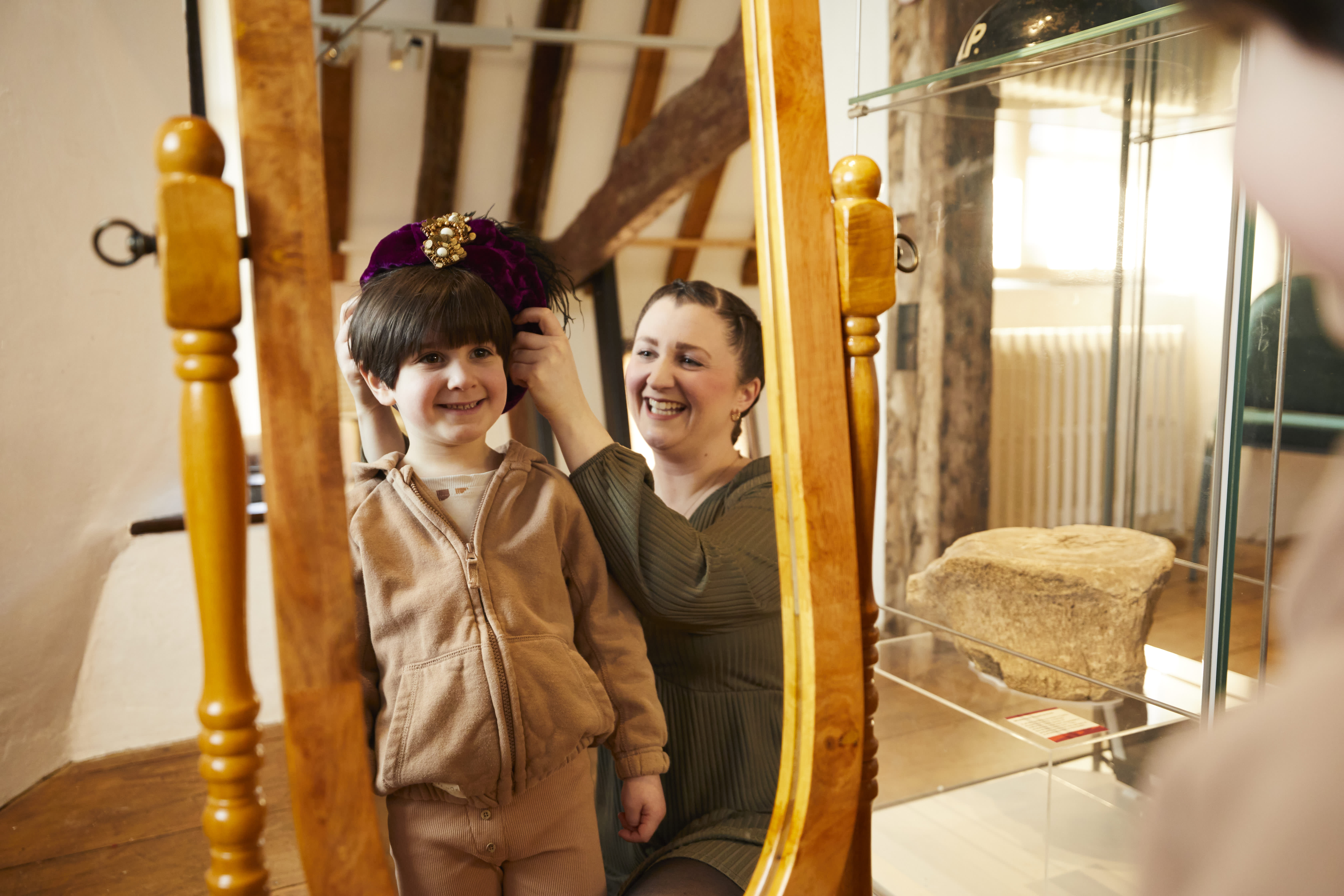 Mother and son standing in front on mirror playing dress up at Tudor House and Garden