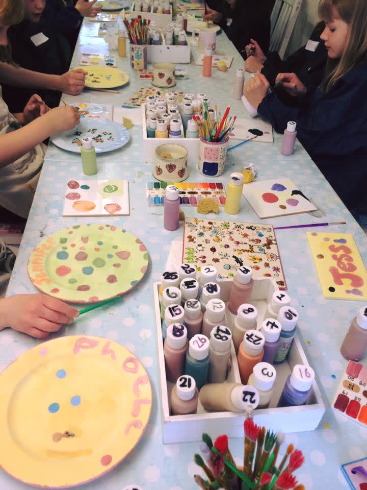 Table laid with lots of pottery activities and children enjoying them