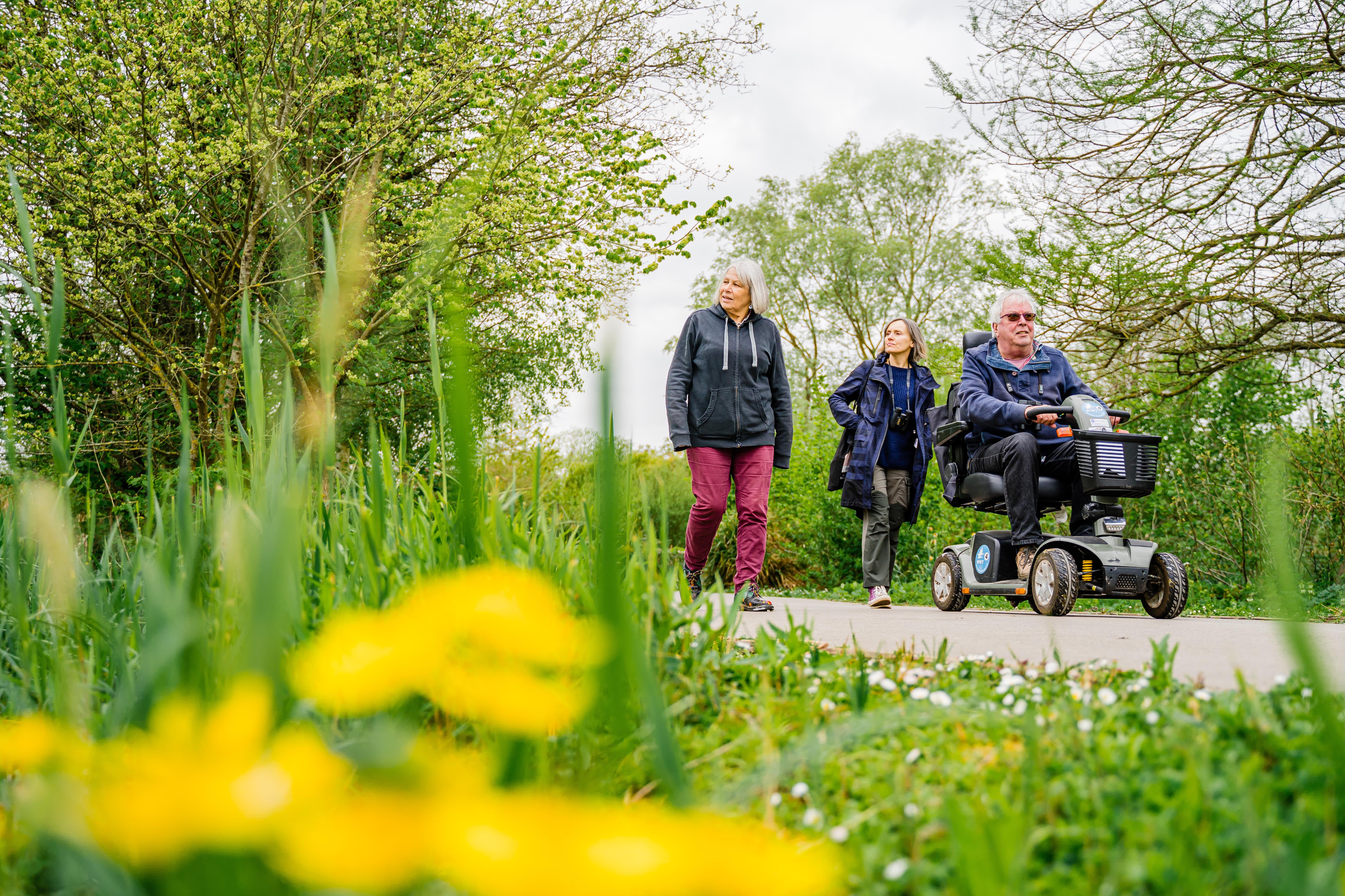 Wheelchair user accompanied by two people walking
