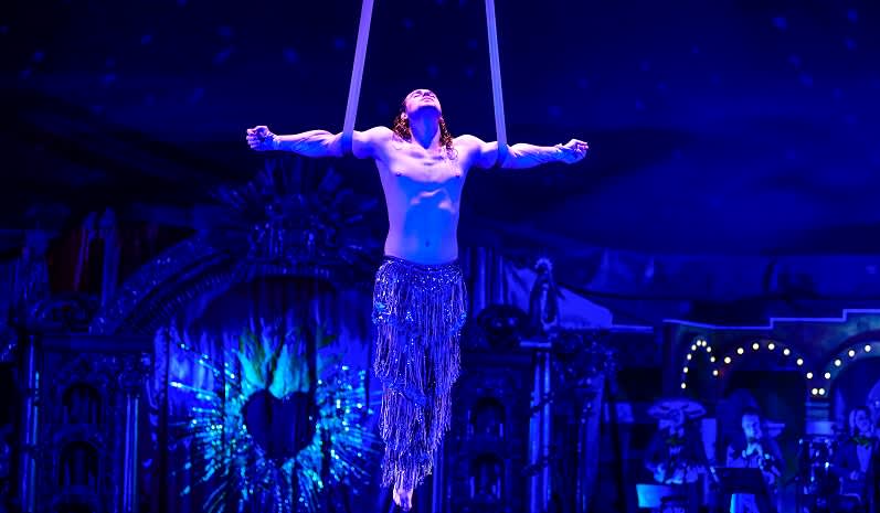 An aerial performer hangs from ribbons from the ceiling