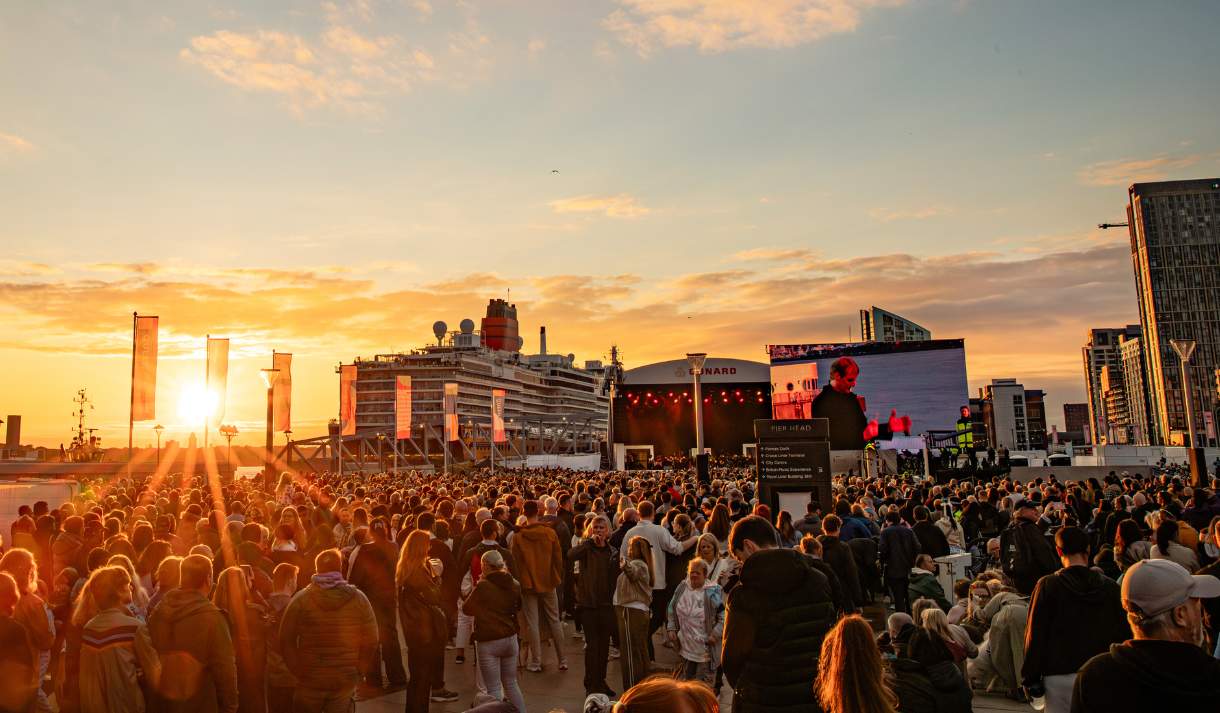 Liverpool Pier Head, busy with visitors and the sun going down across the River creating a golden light