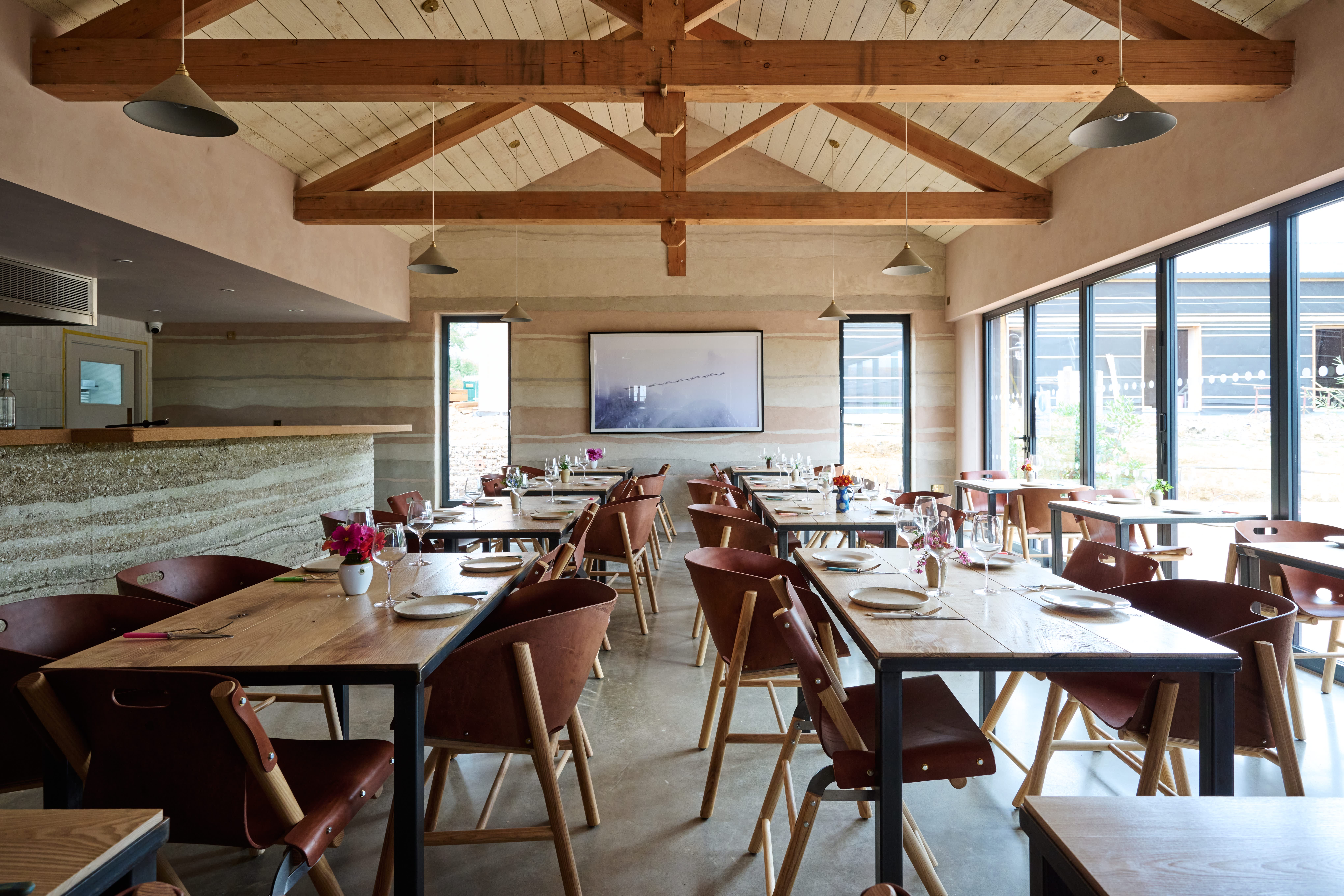 Interior view of wooden tables, chairs and beams in Knepp Wilding kitchen restaurant