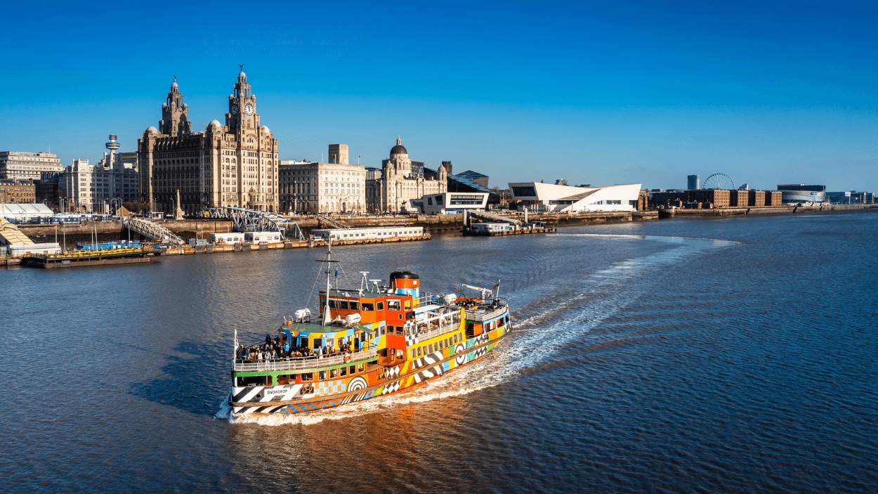 the mersey ferry on the river mersey with the three graces in the background.