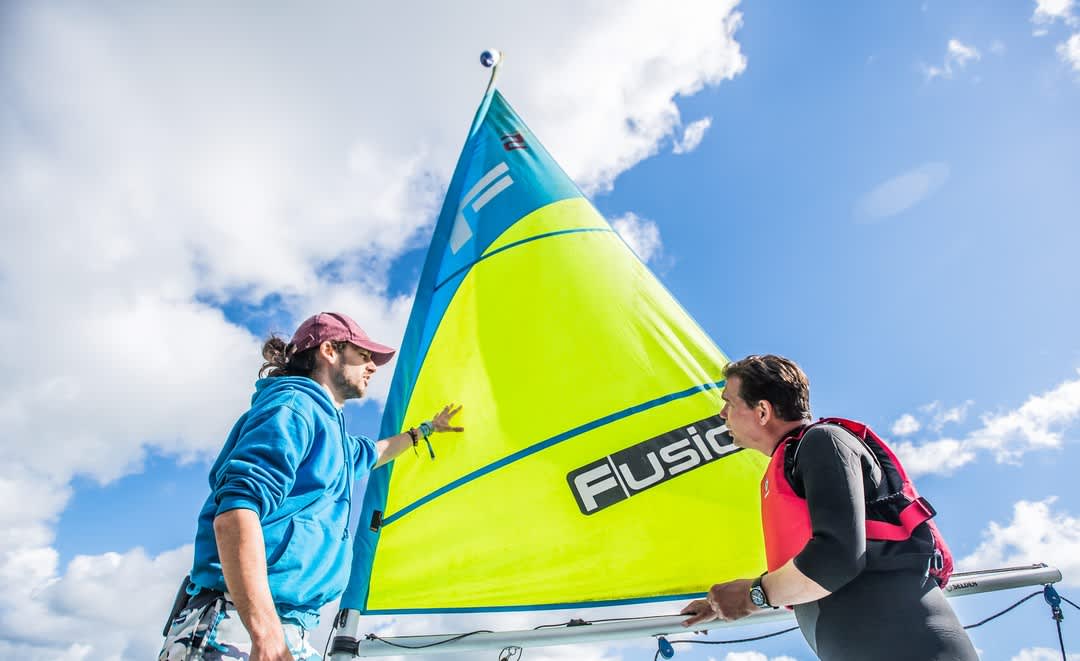 two men in front of a sailing boat