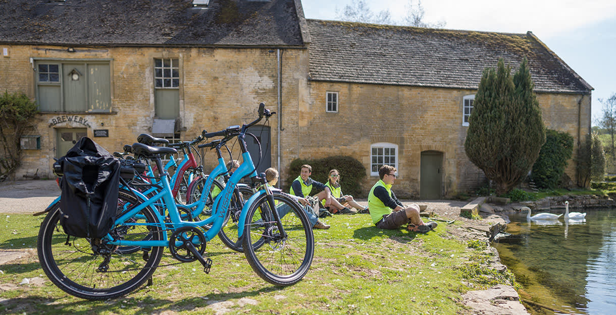 A group of cyclists sitting by a pond