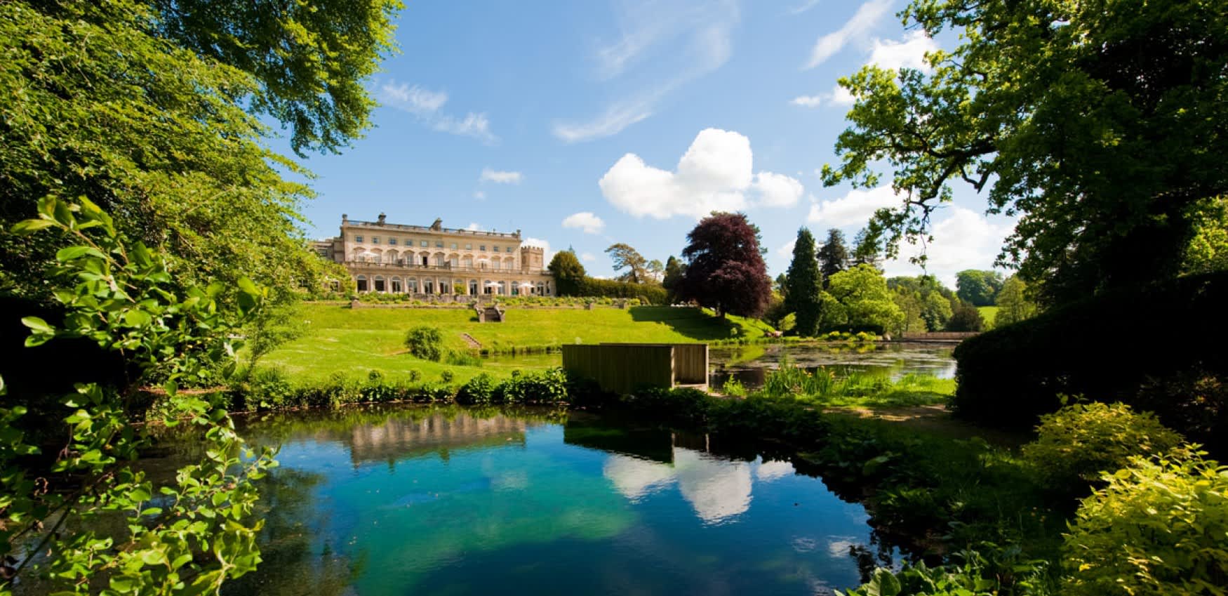The stunning, Grade II listed Cowley Manor mansion lies in the distance with lush green lawns in front leading down to a large pond