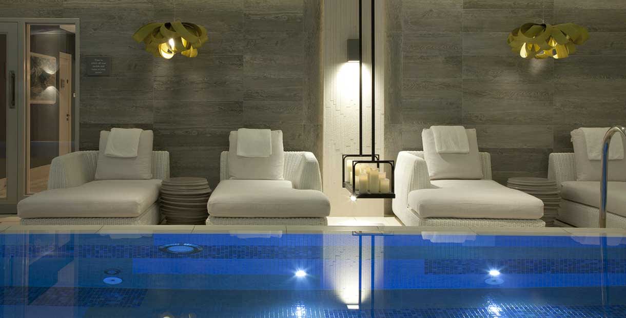 White luxurious loungers surround a tranquil indoor pool at The Dormy House in the Cotswolds