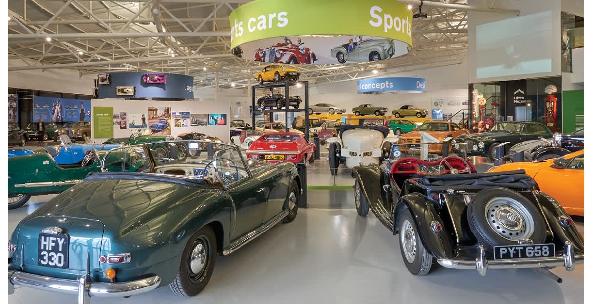 A myriad of classic cars gleam under bright lights in the British Motor Museum