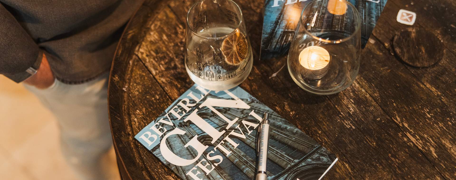 A table with a leaflet for the Beverley Gin Festival, surrounded by drinking glasses.