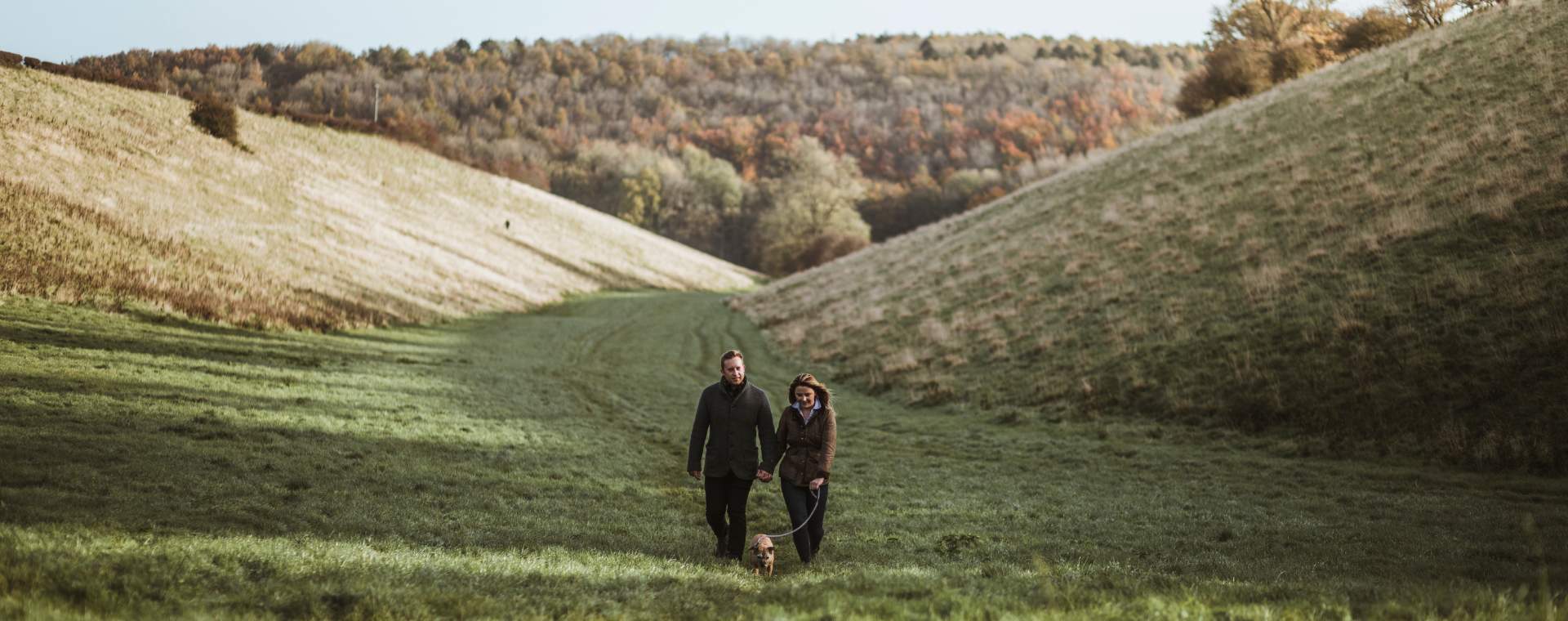A couple walking their dog through a valley in the Yorkshire Wolds in East Yorkshire