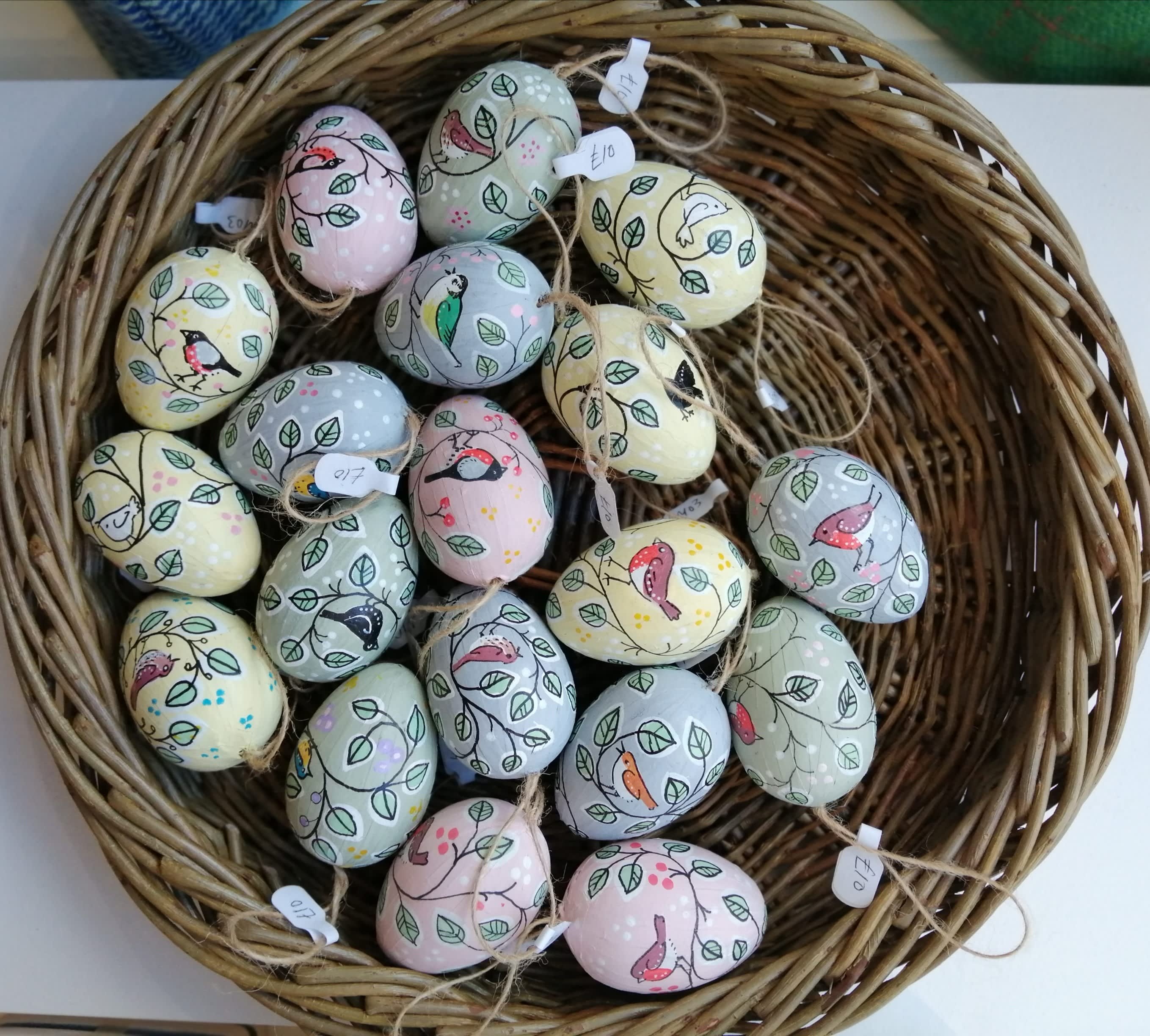 A wicker basket filled with pastel-coloured handpainted eggs from The Gloucester Guild of Craftsman