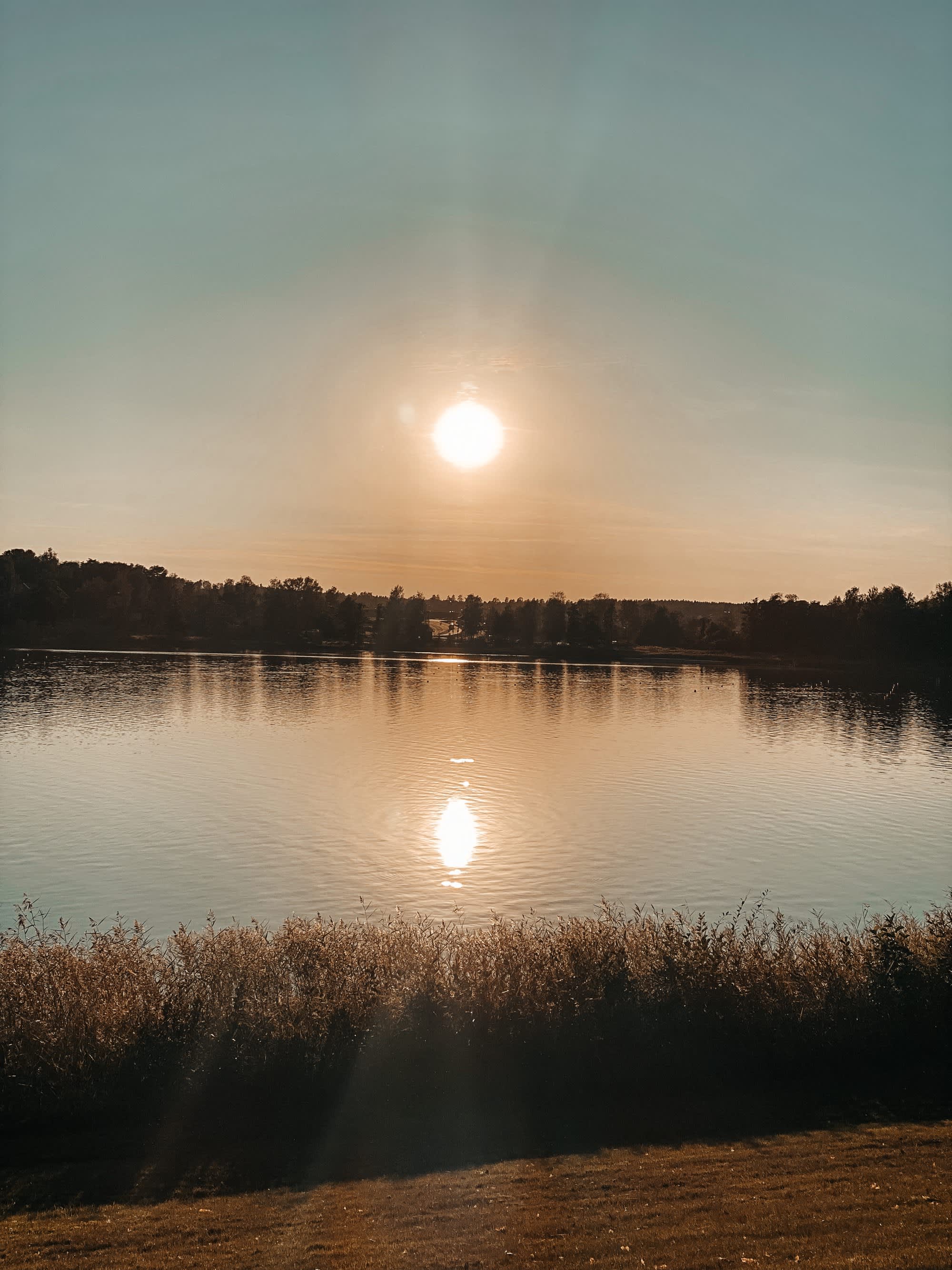 Solnedgang med refleksjon i vannet. Foto
