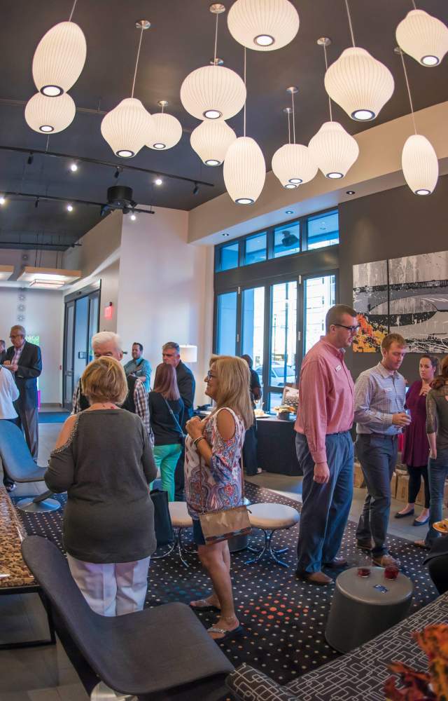 A group of people enjoy a happy hour in the lobby of Aloft South Bend