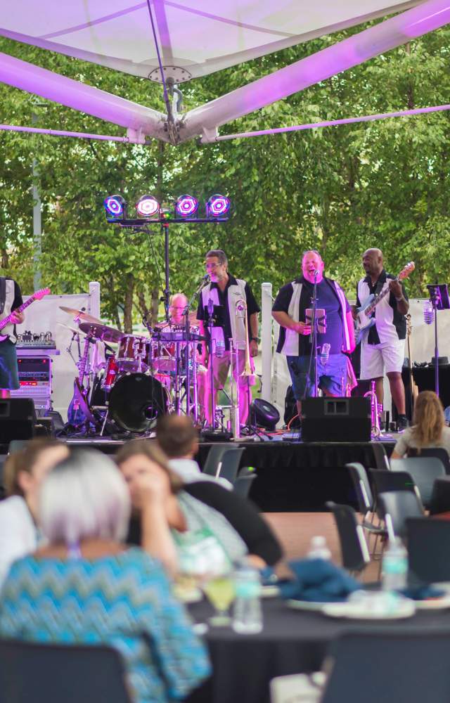 A band plays music at an evening event at the Center Center's Island Park