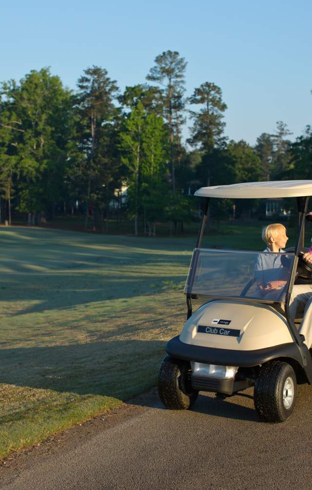 Man and boy riding golf cart at Bartram Trail Golf Course