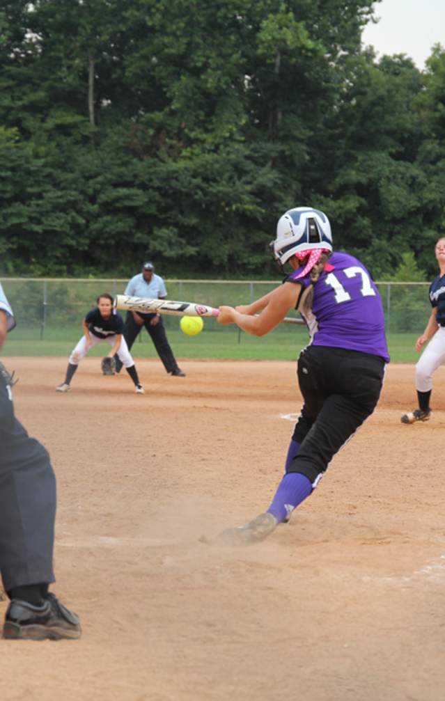 A batter hitting a softball during a game