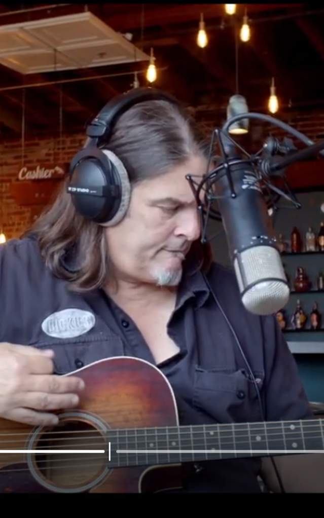 Artist singing and recording while playing guitar in Catoctin Creek Distillery
