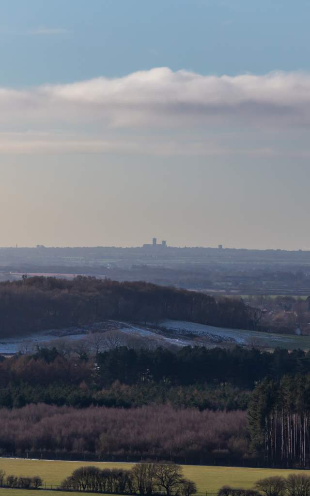 A landscape of the Lincolnshire Wolds in winter with fields in foreground and Lincoln Cathedral in the distance