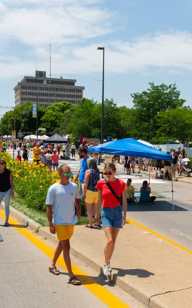 people walking through a sidewalk chalk festival