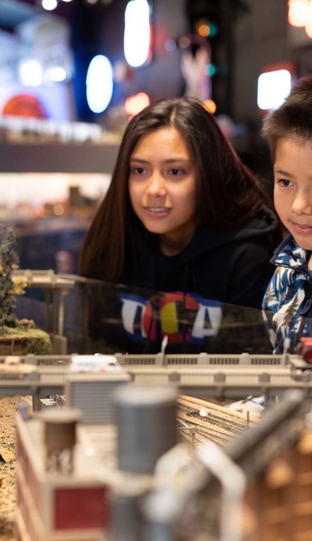 Two young people looking at a model train exhibit at the Colorado Model Railroad Museum