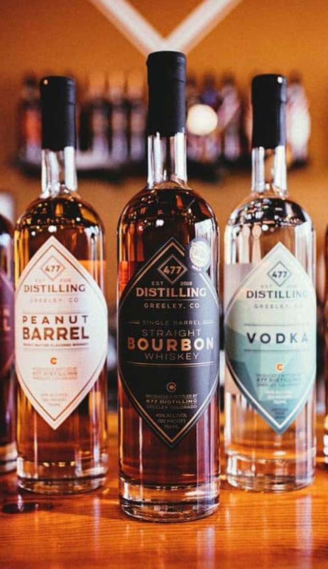 Product photos of 477 Distilling bottles on a wooden bar top
