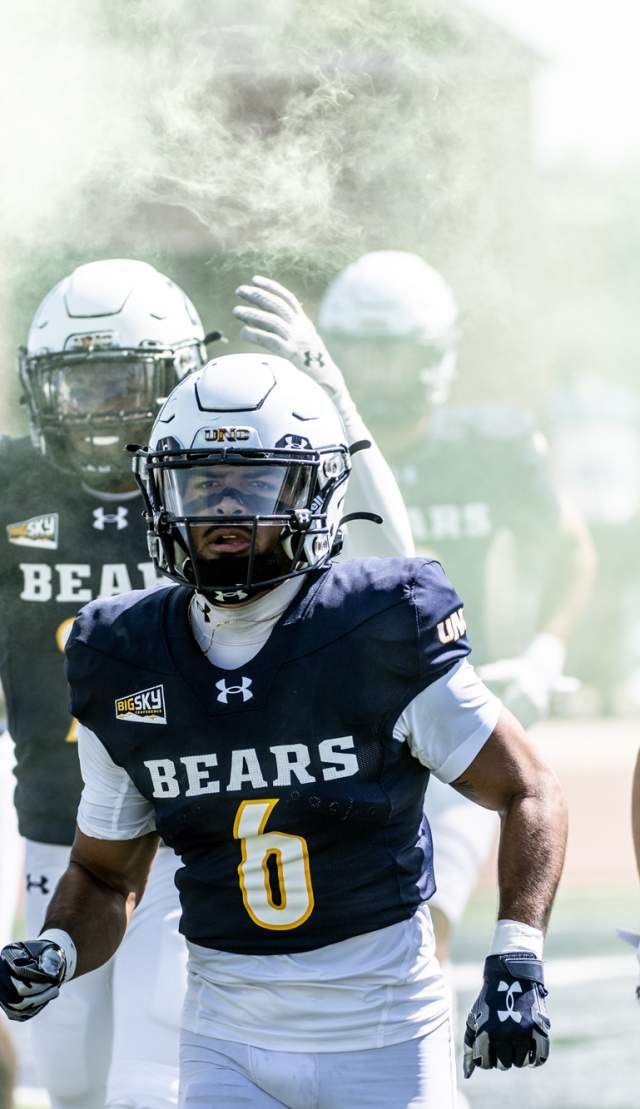 UNC Bears football players entering the field before the start of the game in a cloud of smoke for visual effect