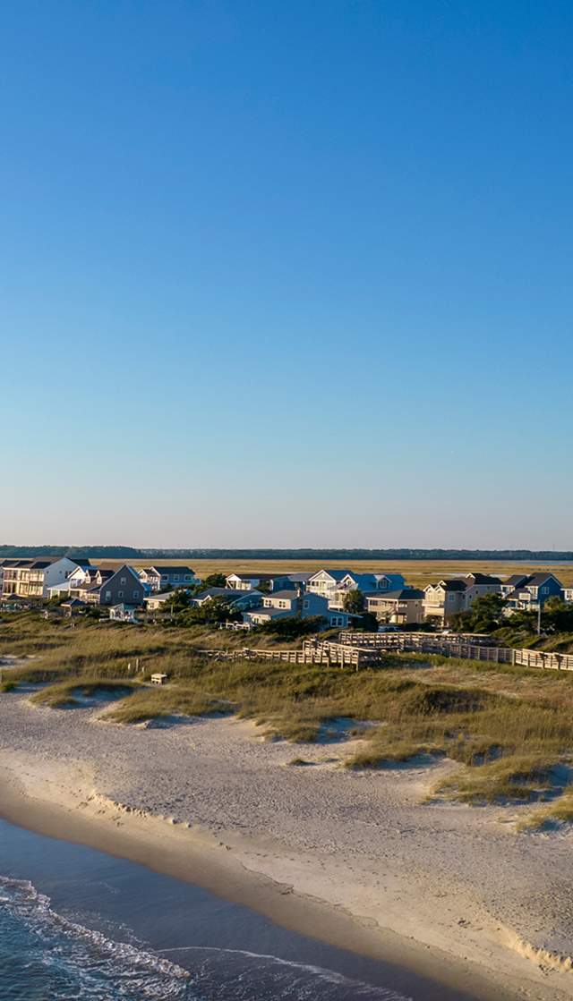 an aerial view of the OKI Lighthouse and Caswell Beach, NC