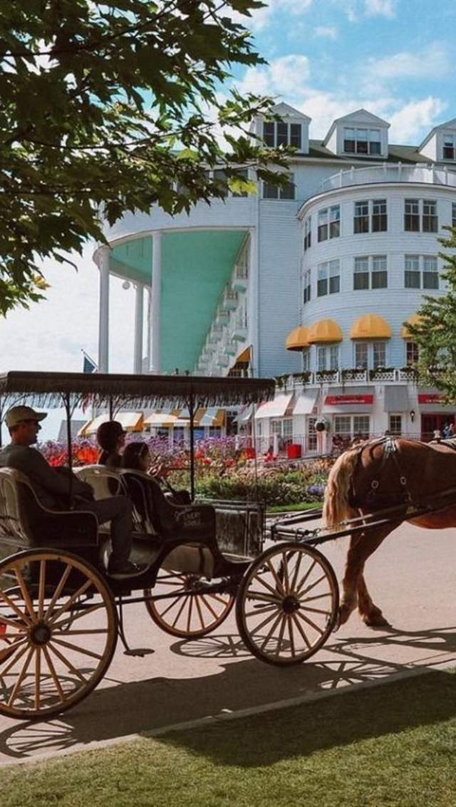 A drive-it-yourself horse carriage on Mackinac Island passes by Grand Hotel as it makes its way up the hill