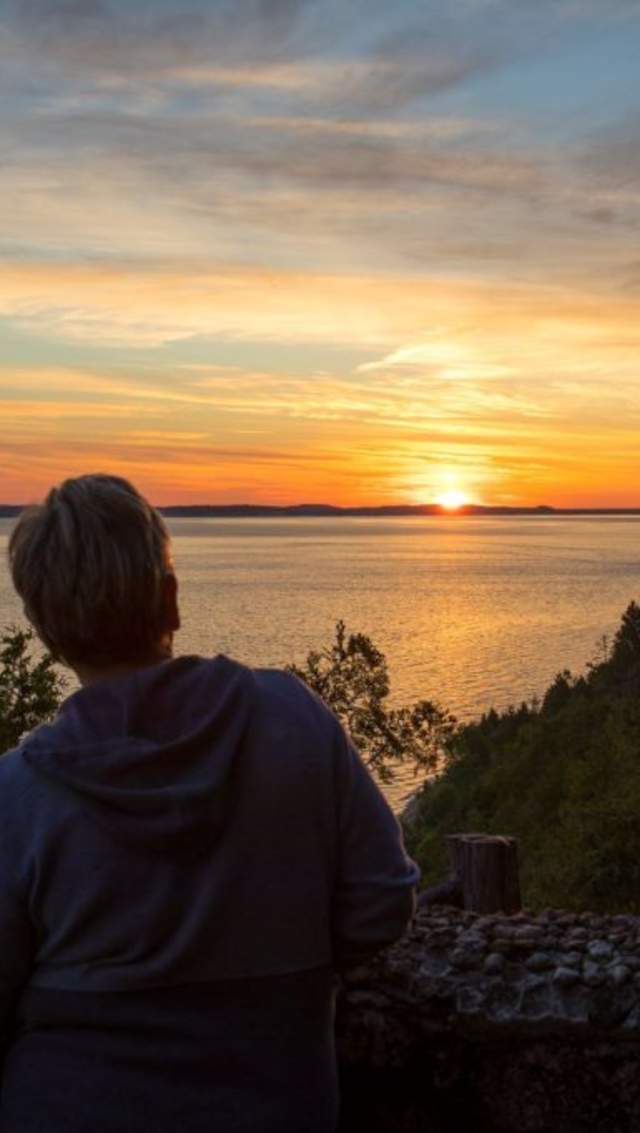 A couple looks out from Mackinac Island’s Sunset Rock at the setting sun over the water