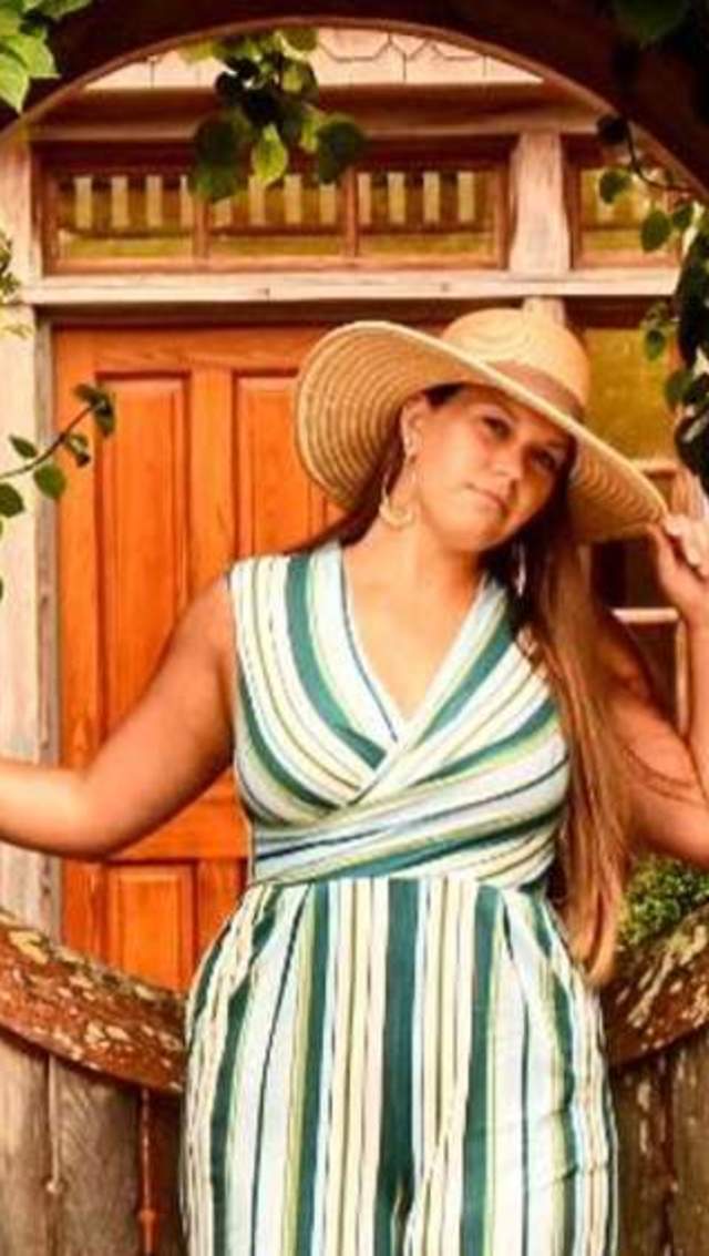 Person posing in front of wooden door with greenery
