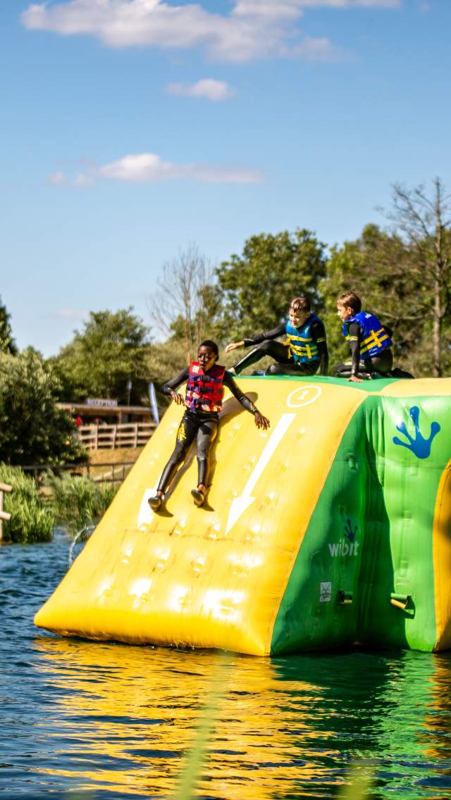 Children on an inflatable slide into the water at Dorset Adventure Park