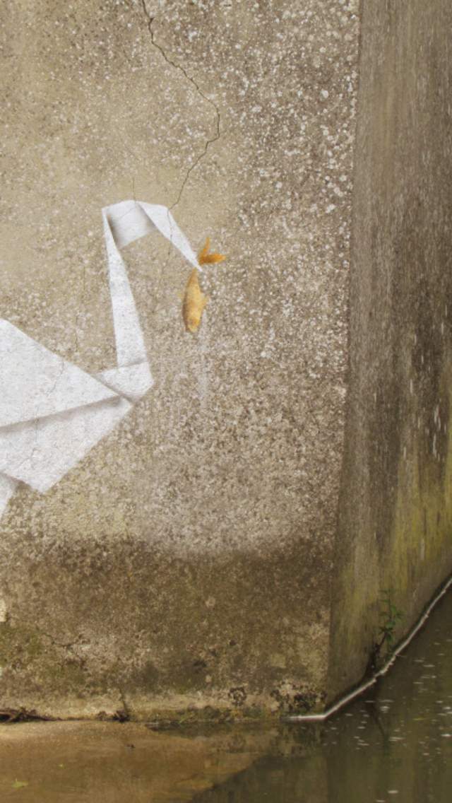Artwork on a wall of an origami crane with a fish a work by artist Banksy in Lyme Regis