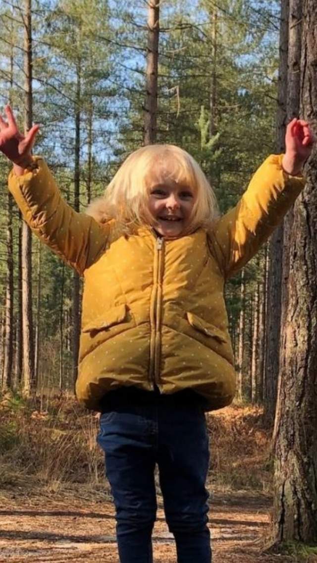 Child standing with their hands in the air in a forest in Dorset