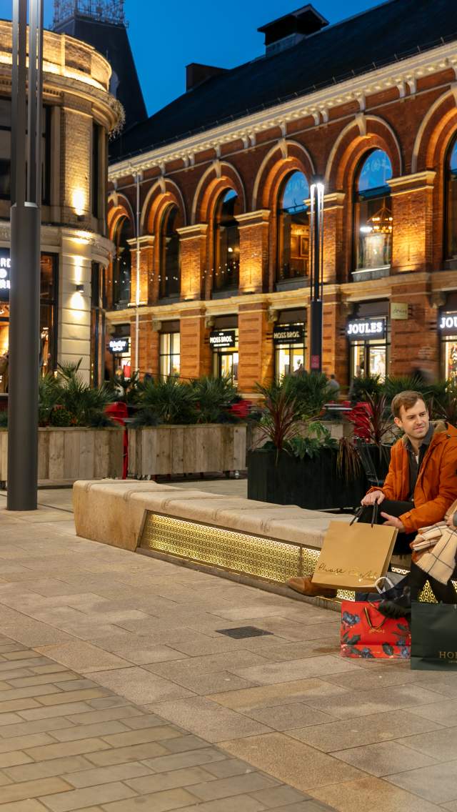 An evening view of the Cornhill Quarter in Lincoln, with a couple shopping in the forefront