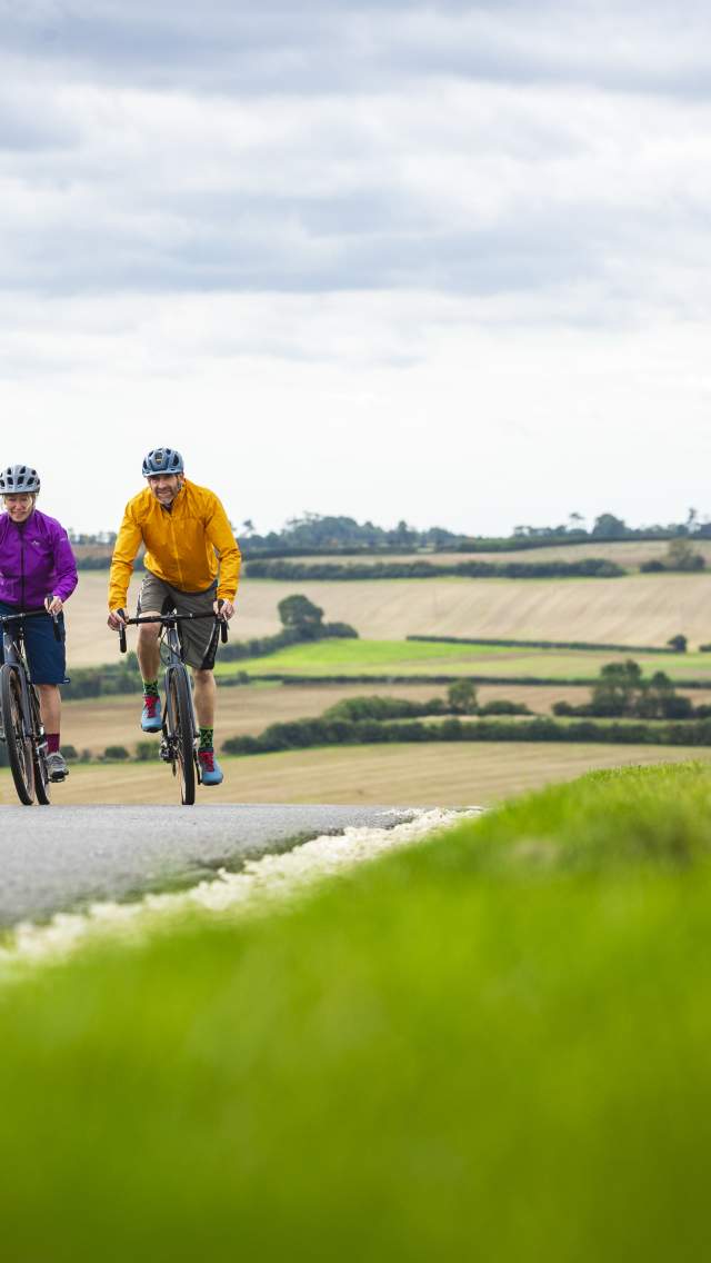 A couple cycling in the Lincolnshire Wolds, with rolling hills in the background