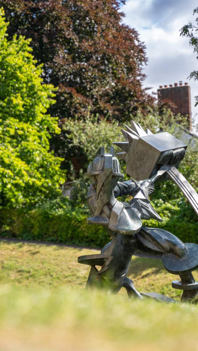 A metal sculpture of a man swinging a tool.