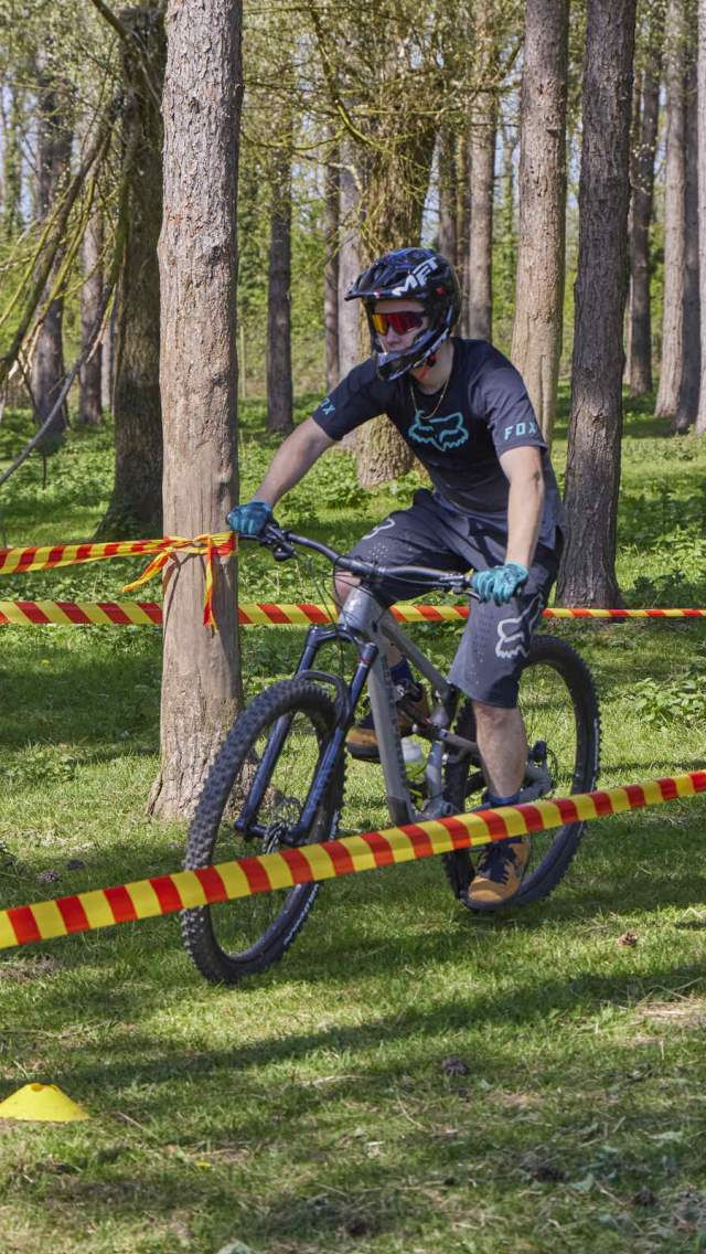 A person riding a bike through the woodlands at the Lincolnshire Wolds Outdoor Festival with a helmet and gloves on.