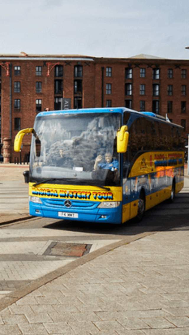 The 'Magical Mystery Tour' coach on Liverpool Albert Dock. The coach is bright yellow and green with rainbow writing on the side