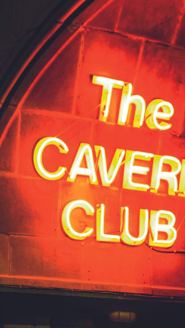 A neon red sign that reads 'Cavern Club' lit up at night time.