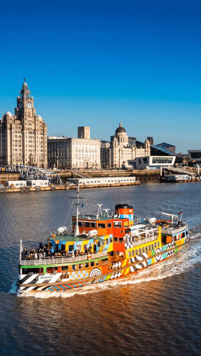 The Mersey Ferry Dazzle ferry, a colourful boat on Liverpool Waterfront with blue skies and Liverpool skyline