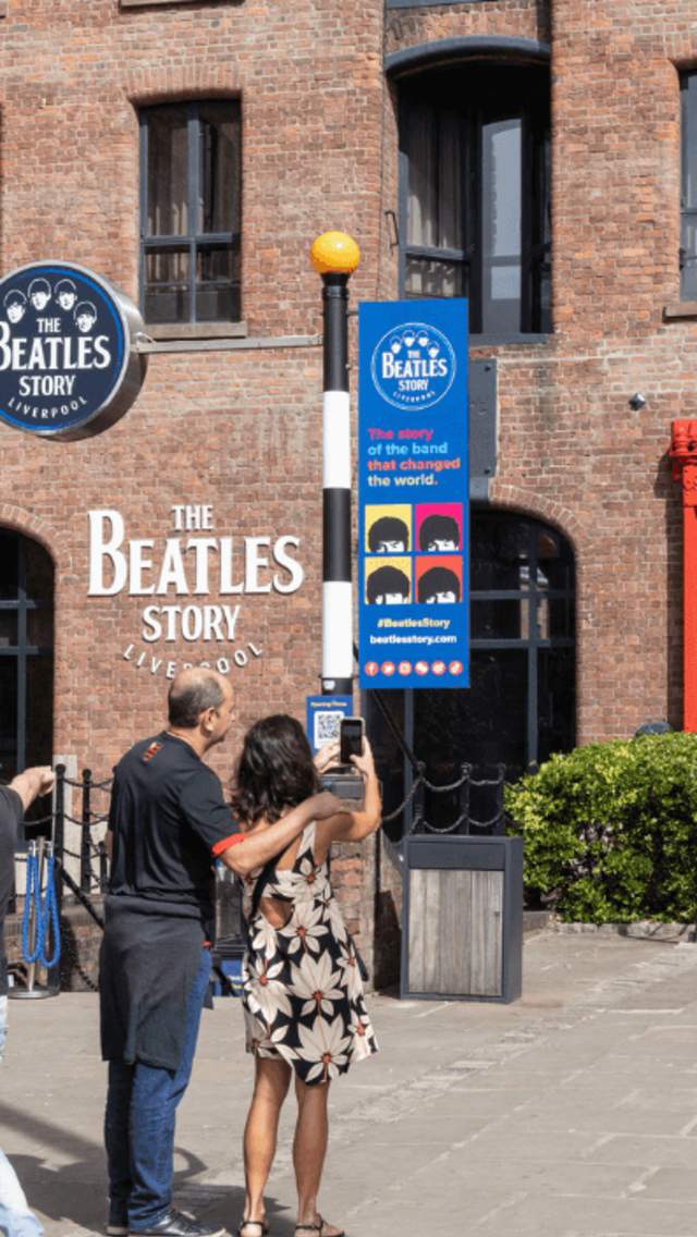 People standing outside the Beatles Story museum, a warehouse style building within the Royal Albert Dock