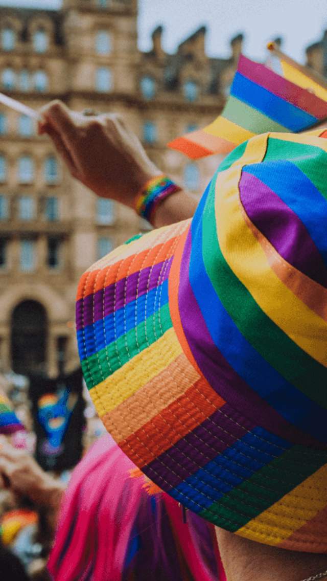 A person wearing a pride rainbow hat in a crowd of people at st George's Plateau where the march is about to begin.