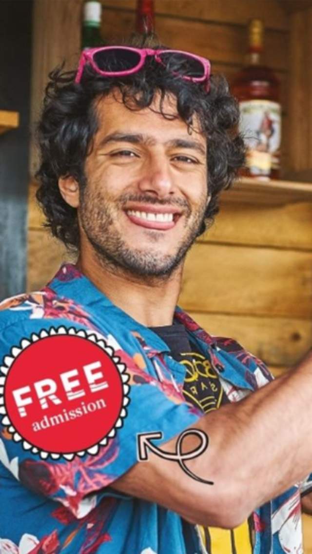 A man holding a cocktail shaker, wearing a Hawaiian shirt and smiling at the camera.