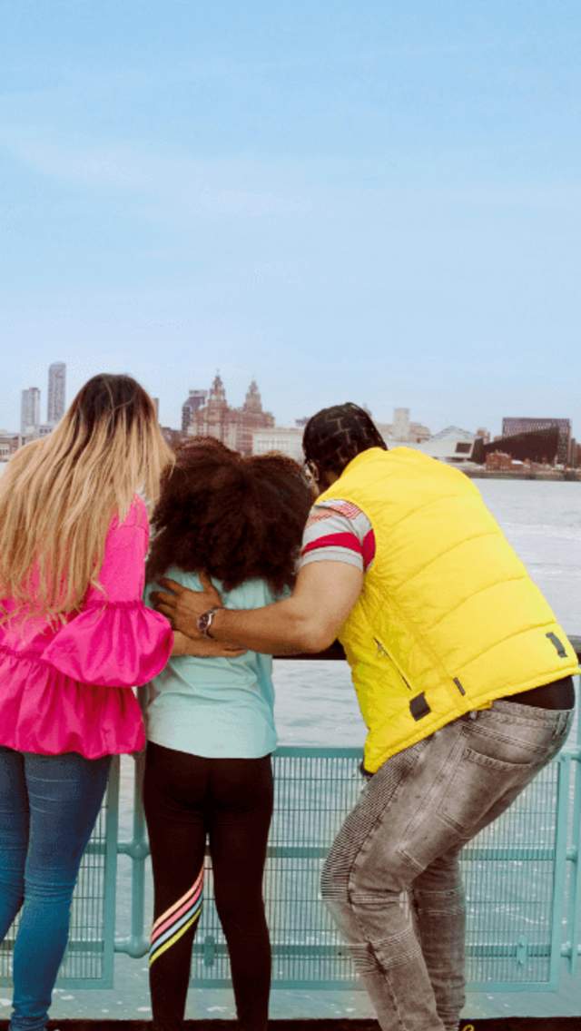 A family with a young girl in between them both look across the River Mersey