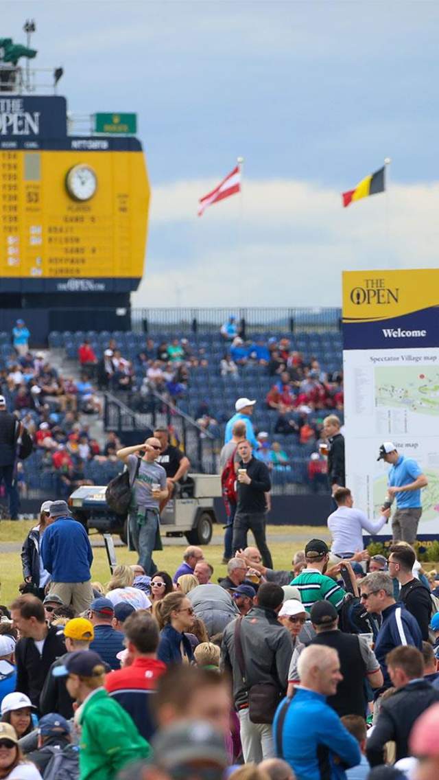 Crowds mingle in front of the grandstand at the 148th Open