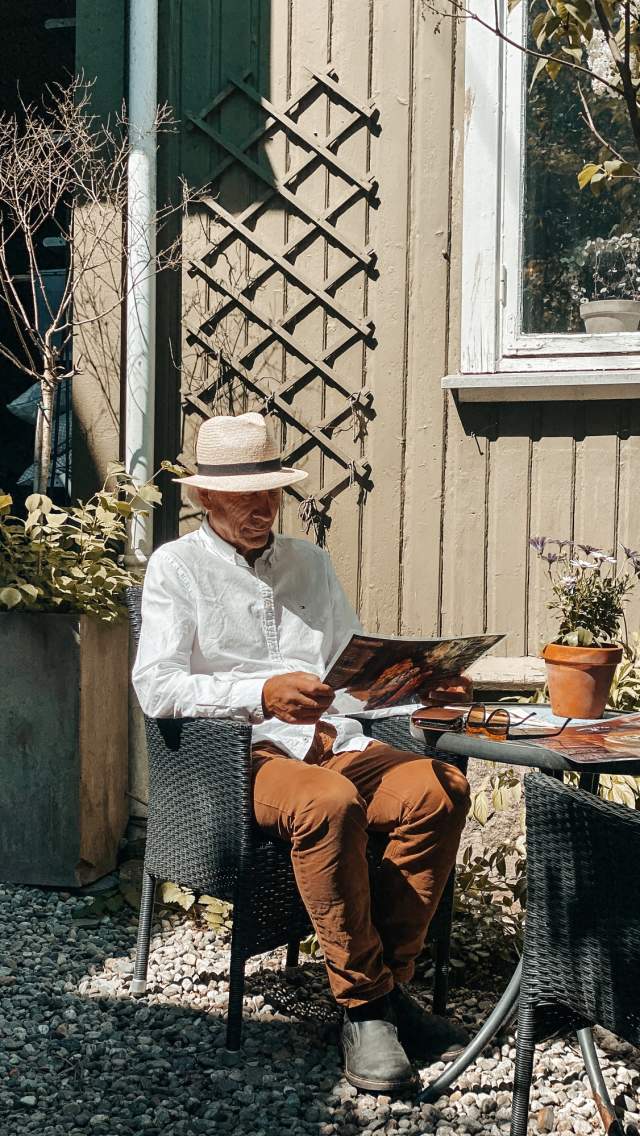 Mann med hatt som sitter og leser avisen på et kafébord i Sarpsborg. Foto.