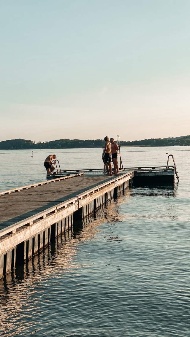Mennesker som bader fra brygga på Høysand. Foto.